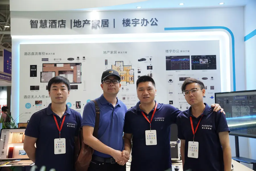 Four exhibition participants pose at the PUGOING booth, with the two in the middle shaking hands